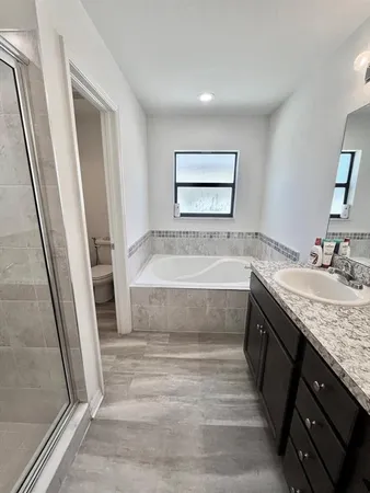 a bathroom with a granite countertop sink a toilet a mirror and vanity