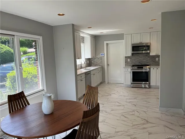 a kitchen with granite countertop a stove a sink dishwasher a dining table and chairs with wooden floor