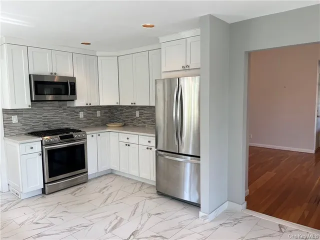 a kitchen with granite countertop a refrigerator stove and microwave