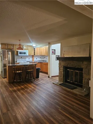 a kitchen with stainless steel appliances wooden floor and hall view
