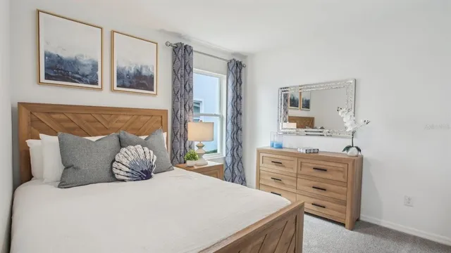 a bedroom with a bed and a potted plant on the dresser