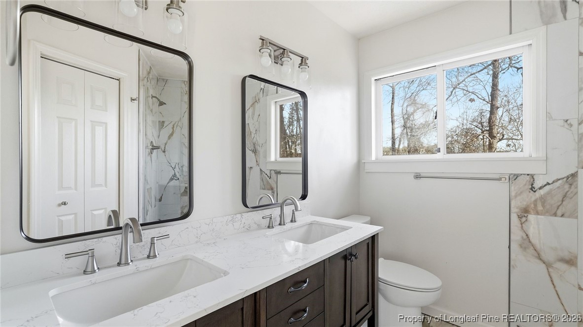 10765 Barker 10 Mile Road St. Pauls, NC 28384 - Photo 16 of 48 a bathroom with double vanity sink toilet and a mirror
