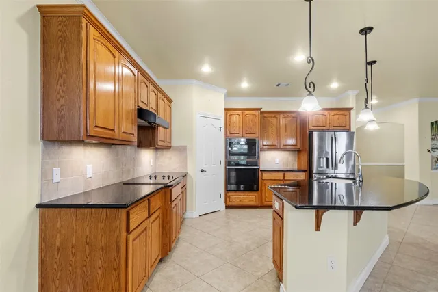 a kitchen with stainless steel appliances granite countertop a refrigerator a stove a sink and a microwave