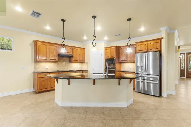 a large kitchen with kitchen island a large counter top space a sink stainless steel appliances and cabinets