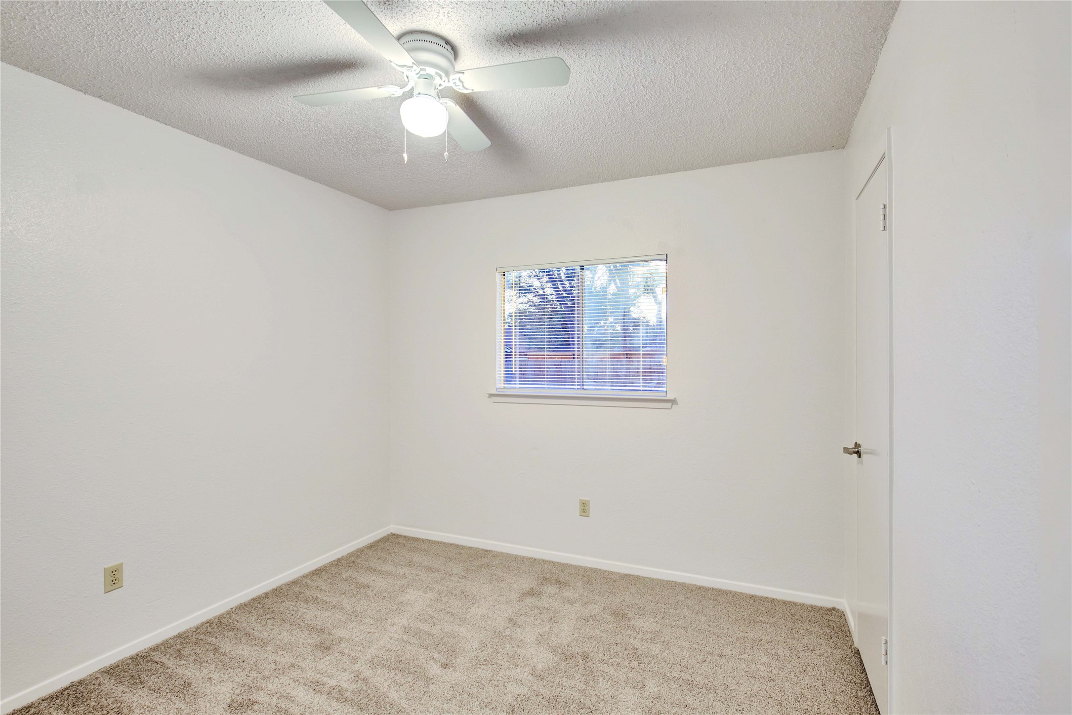2807 Firecrest Drive Austin, TX 78748 - Photo 18 of 30 Neutral-toned carpeted room featuring a window with blinds, a white ceiling fan with integrated lighting, and a white interior door