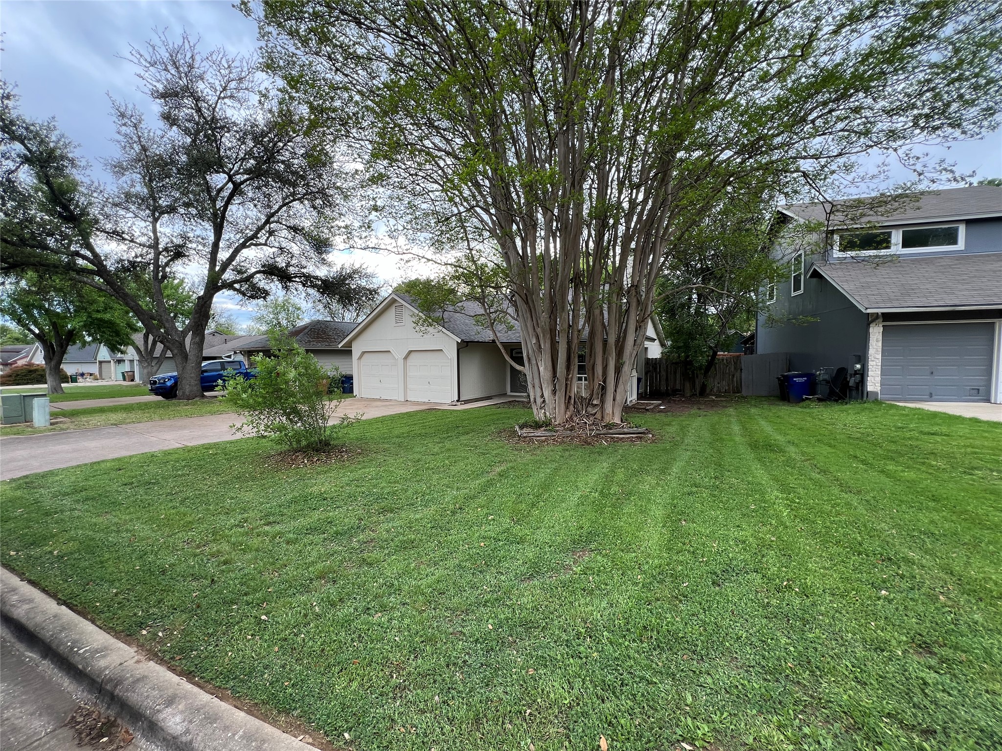 2807 Firecrest Drive Austin, TX 78748 - Photo 30 of 30 Expansive front lawn with mature trees and a paved driveway leading to a two-car garage