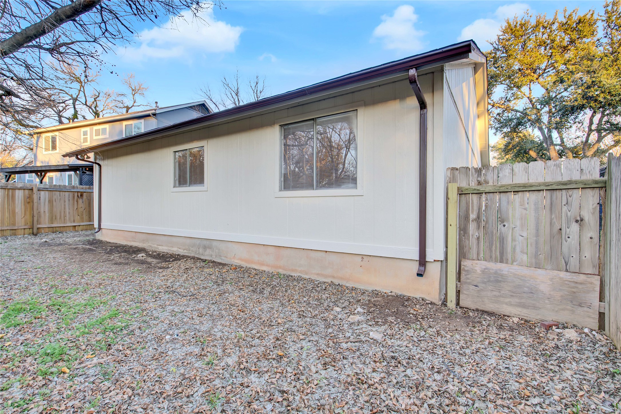 2807 Firecrest Drive Austin, TX 78748 - Photo 3 of 30 White siding exterior with a brown roofline, matching gutters, and a perimeter wood fence
