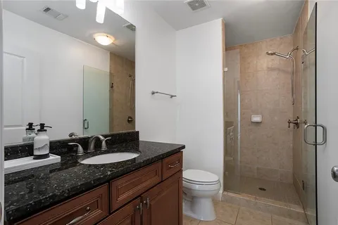 a bathroom with a granite countertop sink toilet and shower