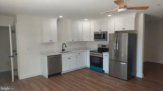 a kitchen with stainless steel appliances granite countertop a refrigerator a stove top oven a sink and dishwasher with wooden floor