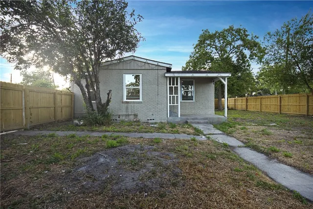 a backyard of a house with plants and large tree