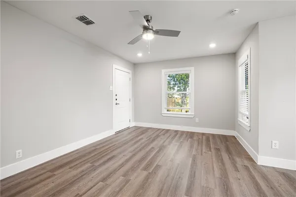 an empty room with wooden floor and windows