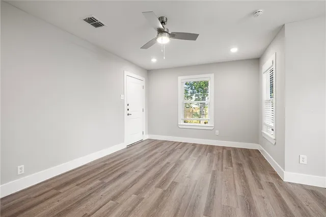 an empty room with wooden floor and windows