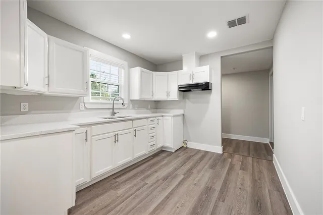 a kitchen with white cabinets appliances a sink and a window