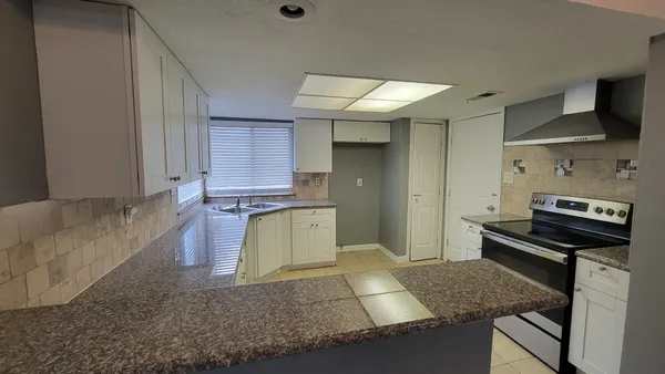 a kitchen with granite countertop a stove a sink and a refrigerator