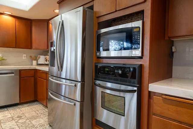 a kitchen with a sink a counter top space stainless steel appliances and a large window