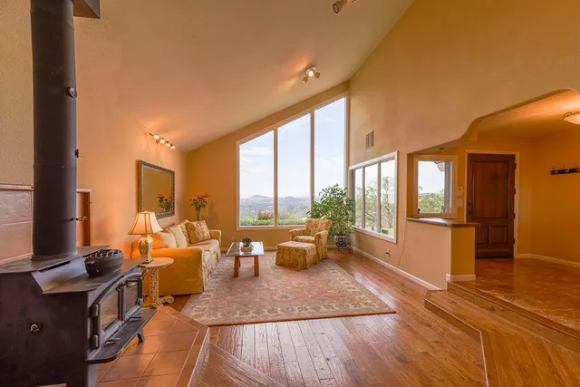 a living room with furniture large windows wooden floor and a table