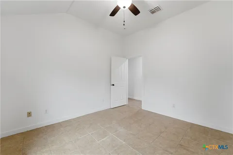 an empty room with a ceiling fan and window
