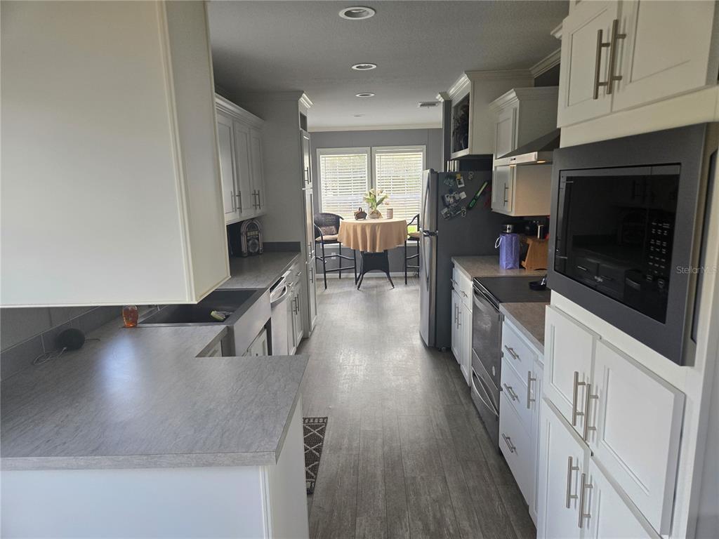 1981 Southeast Piggy Back Road Arcadia, FL 34266 - Photo 5 of 19 a kitchen with stainless steel appliances granite countertop a stove a refrigerator a sink a dining table and chairs with wooden floor