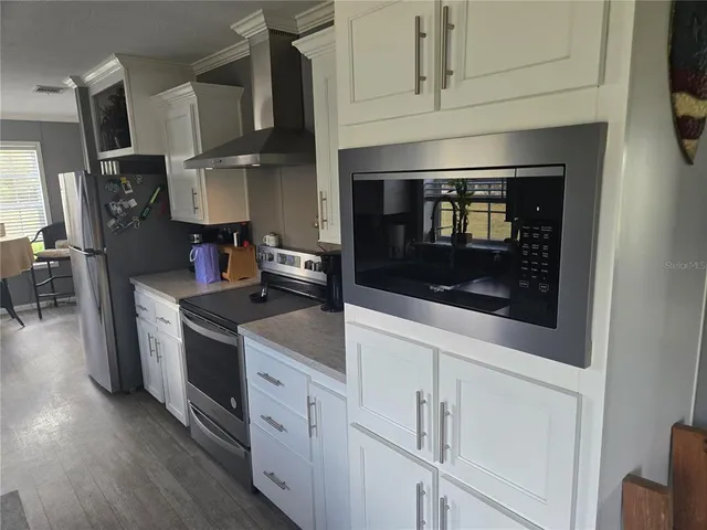 a kitchen with stainless steel appliances white cabinets and a stove top oven