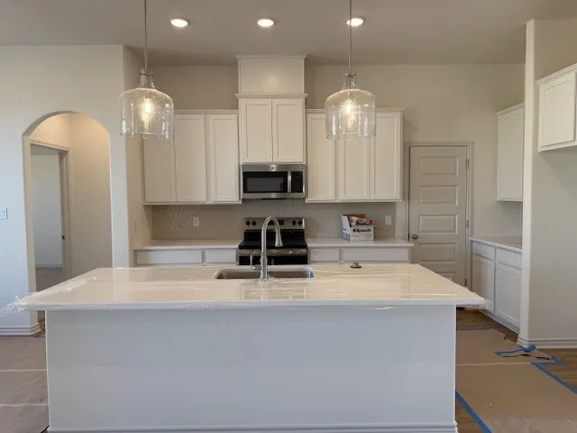 a large white kitchen with lots of counter space a sink and appliances