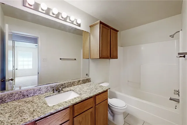 a bathroom with a granite countertop sink a toilet and shower