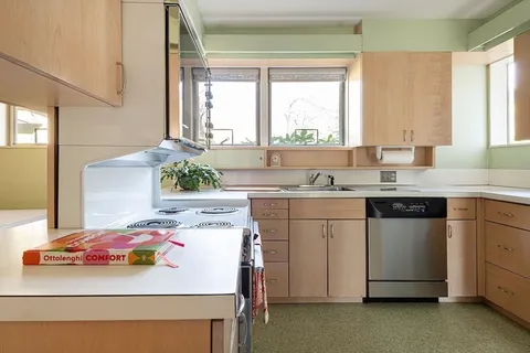 a kitchen with a sink a stove and white cabinets