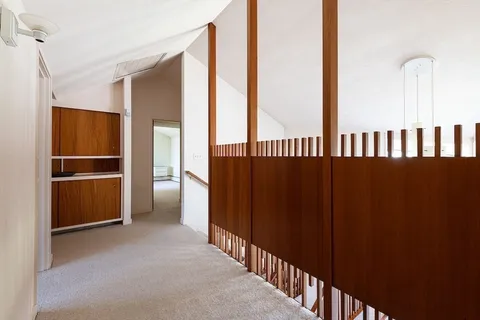 a view of a hallway with wooden floor and windows