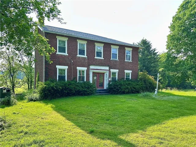 a front view of a house with garden and trees