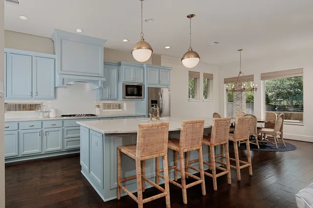 a large kitchen with granite countertop a stove a sink a dining table and chairs