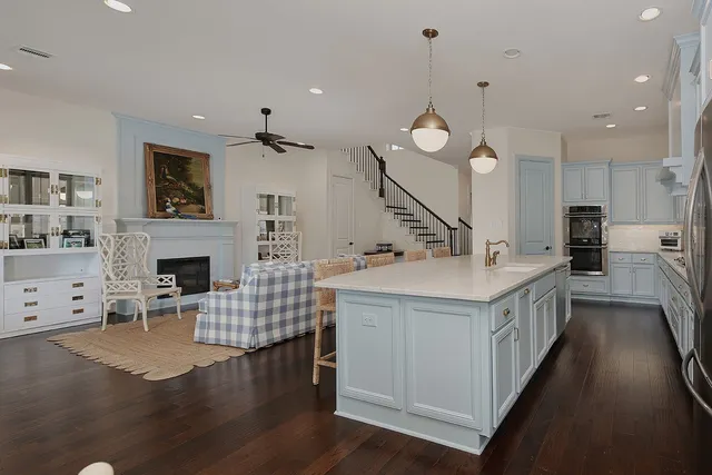 a kitchen with kitchen island granite countertop a sink a counter top space a fireplace and cabinets