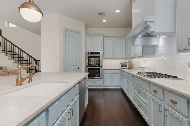 a kitchen with kitchen island granite countertop a sink a stove oven and white cabinets
