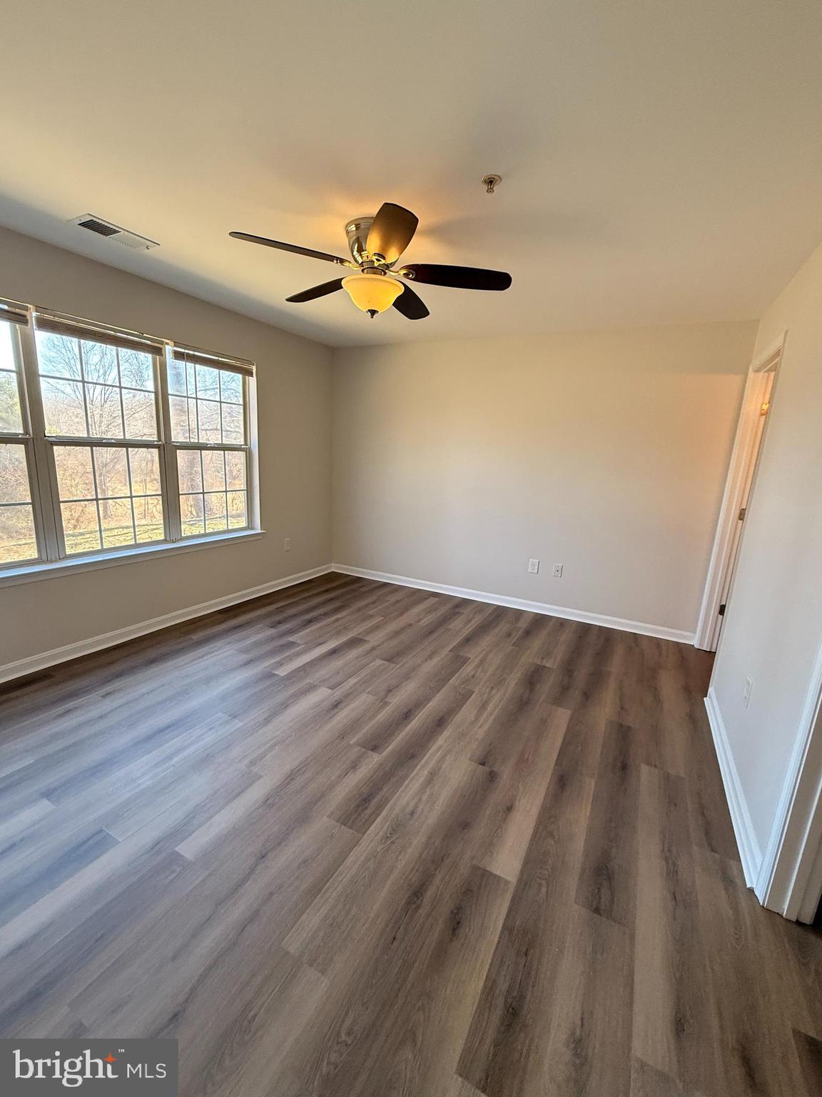 8801 Stoneridge Circle, Unit T2 Baltimore, MD 21208 - Photo 19 of 24 an empty room with wooden floor fan and windows