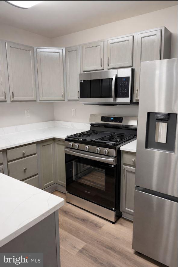 8801 Stoneridge Circle, Unit T2 Baltimore, MD 21208 - Photo 5 of 24 a kitchen with cabinets stainless steel appliances and wooden floor