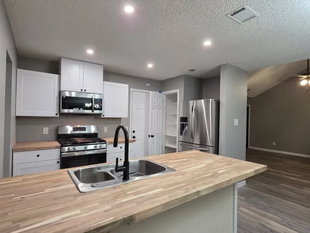a kitchen with stainless steel appliances granite countertop a sink refrigerator and cabinets