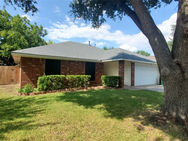 a view of a house with a big yard plants and large tree