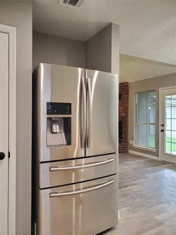 a close view of a refrigerator in kitchen and stainless steel appliances wooden floor