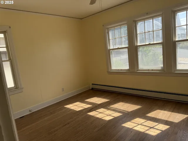a view of an empty room with a window and wooden floor