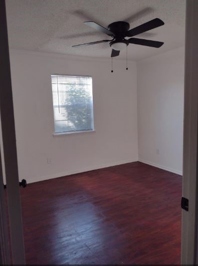 6432 Bankside Drive Houston, TX 77096 - Photo 9 of 14 an empty room with wooden floor fan and windows