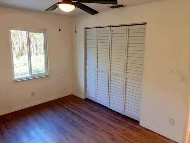 an empty room with wooden floor cabinet and windows