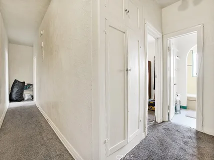 a view of a hallway with wooden floor and a bathroom