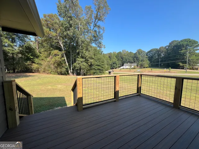 a view of house with wooden fence and a large tree