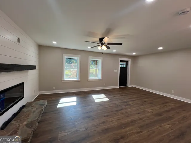 a view of an empty room with wooden floor fireplace and a window