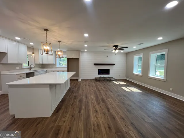 a large kitchen with kitchen island a stove a sink dishwasher and white cabinets with wooden floor