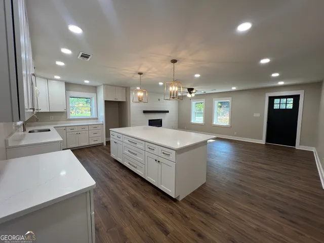a large white kitchen with a large island oven a stove with wooden floors