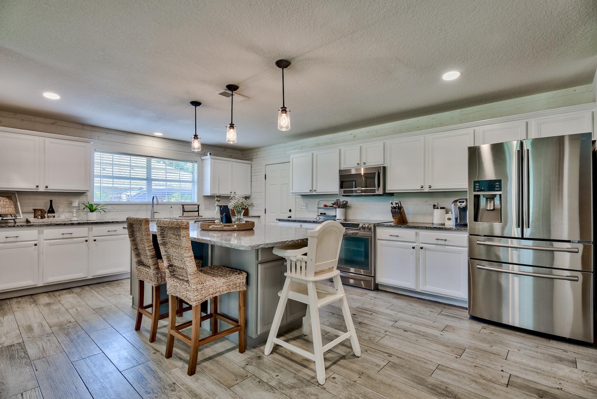 43 East Shipwreck Road Santa Rosa Beach, FL 32459 - Photo 8 of 40 a kitchen with stainless steel appliances granite countertop a dining table chairs refrigerator and microwave