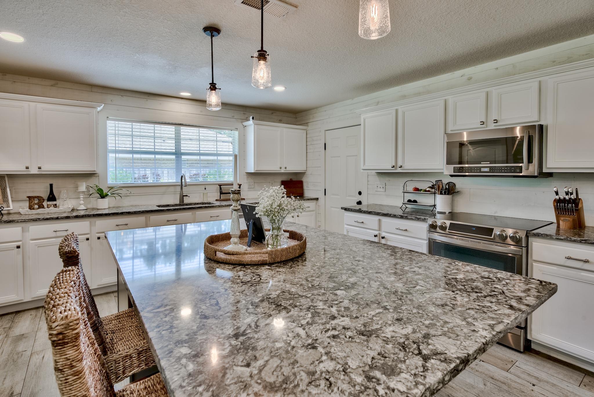 43 East Shipwreck Road Santa Rosa Beach, FL 32459 - Photo 9 of 40 a kitchen with stainless steel appliances granite countertop a sink a stove a window cabinets and a dining table