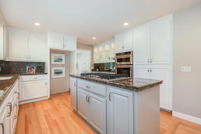 a kitchen with stainless steel appliances granite countertop a stove top oven a sink and white cabinets