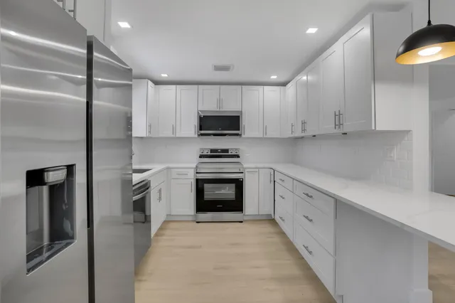 a kitchen with granite countertop white cabinets and stainless steel appliances