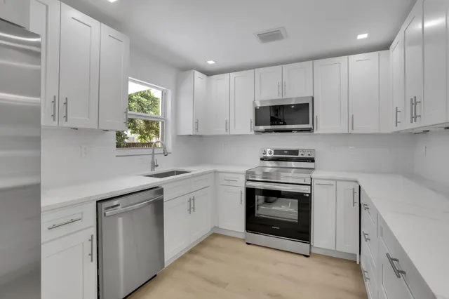 a kitchen with cabinets stainless steel appliances and a window
