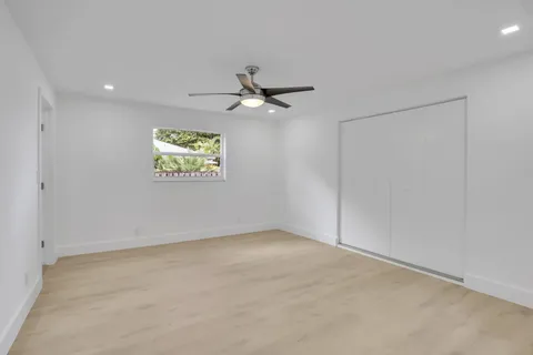 an empty room with windows and fan